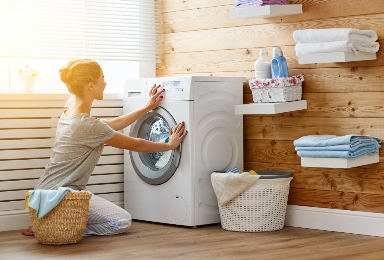 Woman using a washing machine in a laundry room with blinds as laundry room window treatments at House to a Home Interiors near Springfield, Illinois (IL)