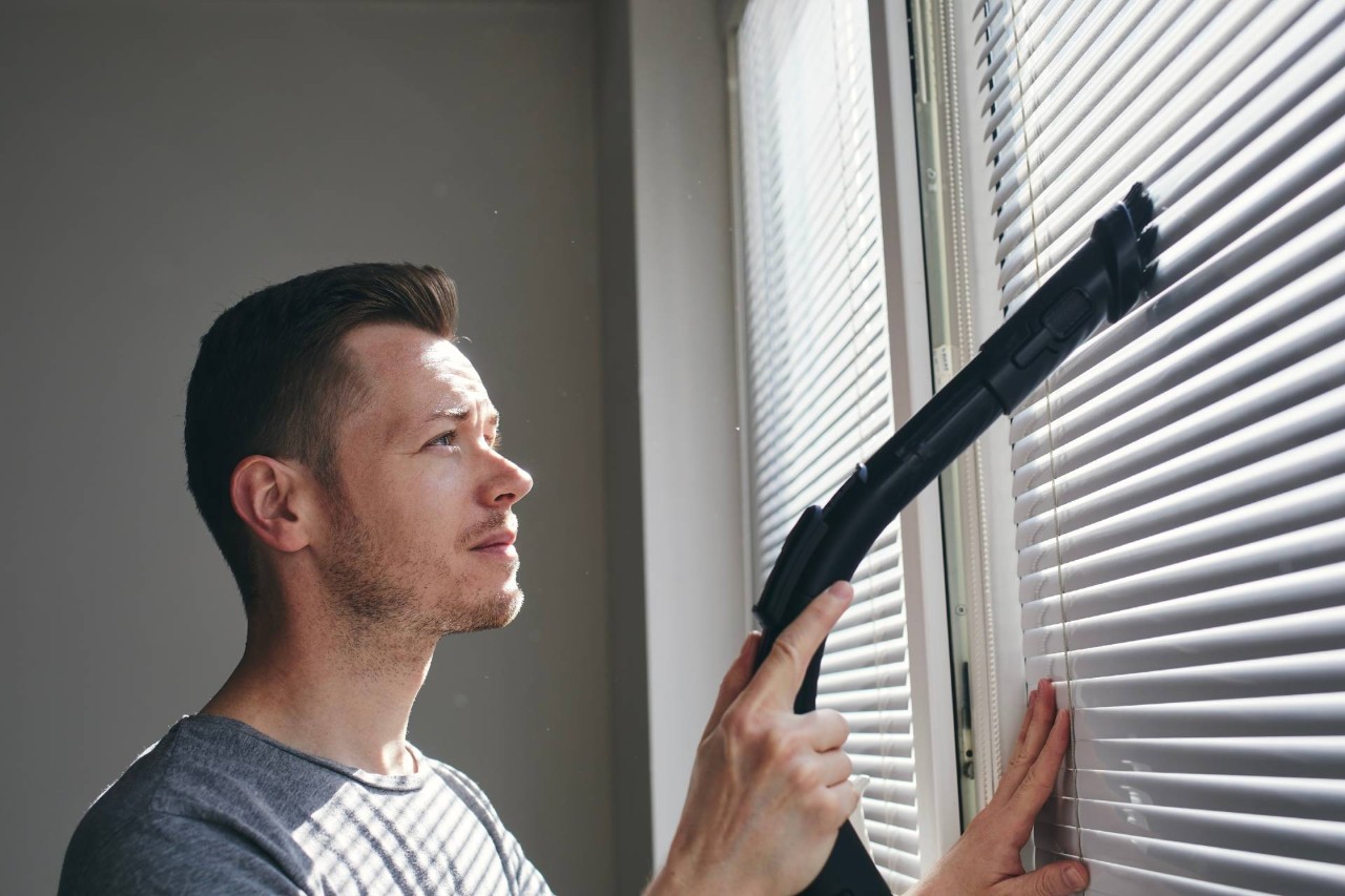 A person using their brush attachment from a vacuum to dust their window blinds at House To A Home Interiors Near Springfield, Illinois (IL)